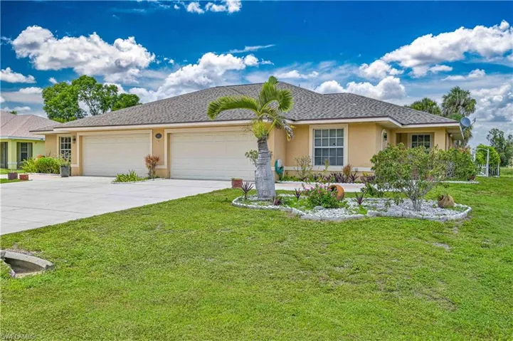 Contemporary stucco exterior with a gray shingle roof, dual garage doors, a concrete driveway, and a landscaped front yard with a palm tree