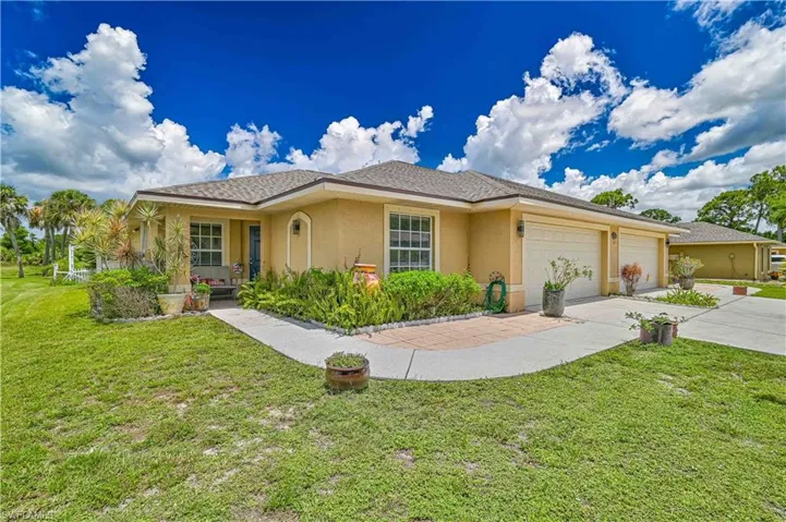 Stucco exterior with a shingled roof, featuring a paved driveway leading to a two-car garage
