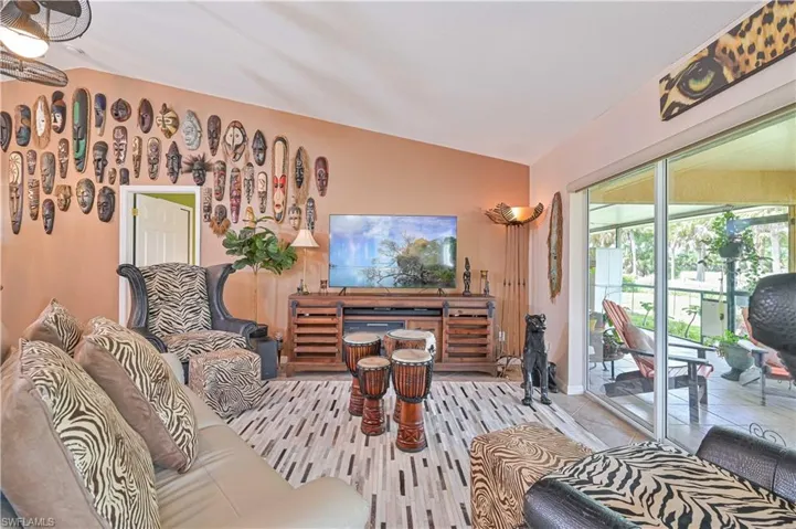 Spacious living area featuring vaulted ceilings, a ceiling fan, and sliding glass doors opening to an outdoor patio