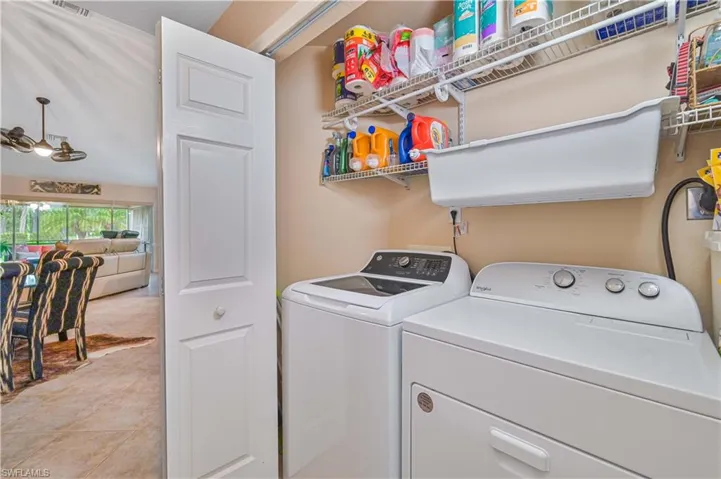 Dedicated laundry area featuring a full-size washer and dryer, wall-mounted shelving, and a utility sink