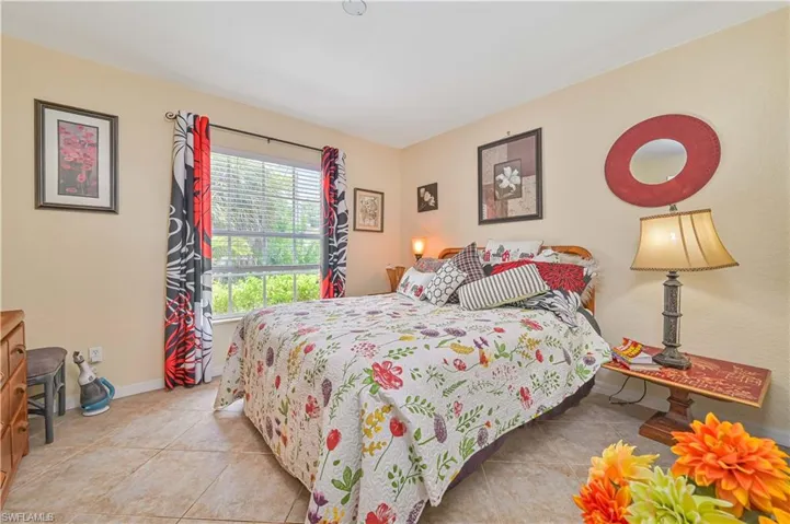Bedroom featuring a window with horizontal blinds, neutral wall tones, and tile flooring