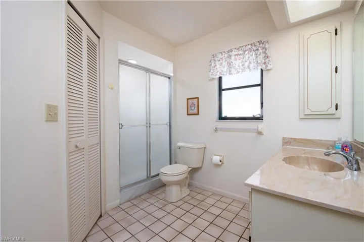 Bathroom featuring a single vanity with an integrated basin, a stall shower with sliding frosted glass doors, and louvered bifold doors