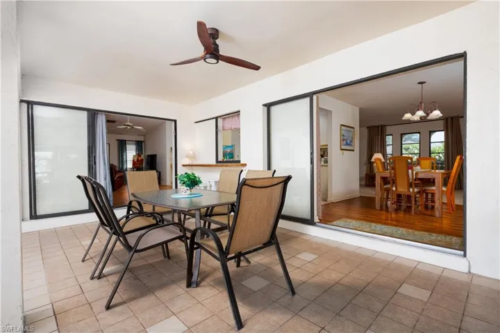 Tiled patio with a ceiling fan, featuring sliding glass doors and an open doorway to interior spaces with wood-finish flooring