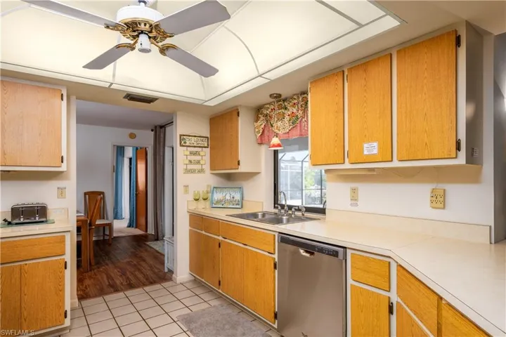 Kitchen featuring wood-finish cabinetry, tile flooring, and a stainless steel dishwasher
