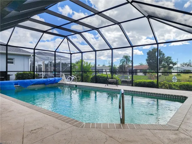 Screened-in pool enclosure featuring a rectangular pool with integrated steps, a brick coping, and a textured concrete deck