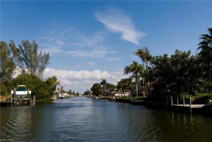 Waterfront property featuring a private boat lift, multiple boat slips, mature tropical landscaping, and a direct canal access