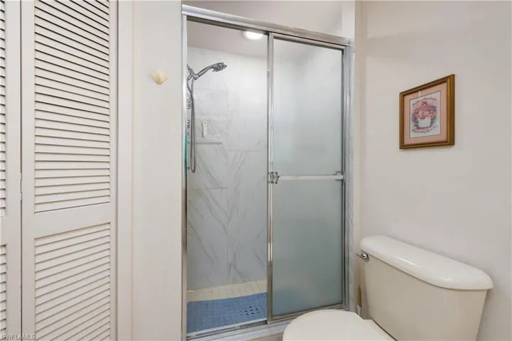 Shower enclosure featuring sliding glass doors and white-tiled walls
