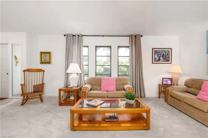Carpeted interior space featuring white walls and a pair of tall, arched windows with dark frames