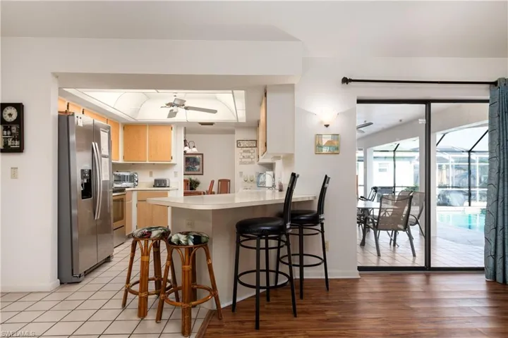 Kitchen with wood cabinetry and stainless steel appliances, featuring a breakfast bar with countertop seating