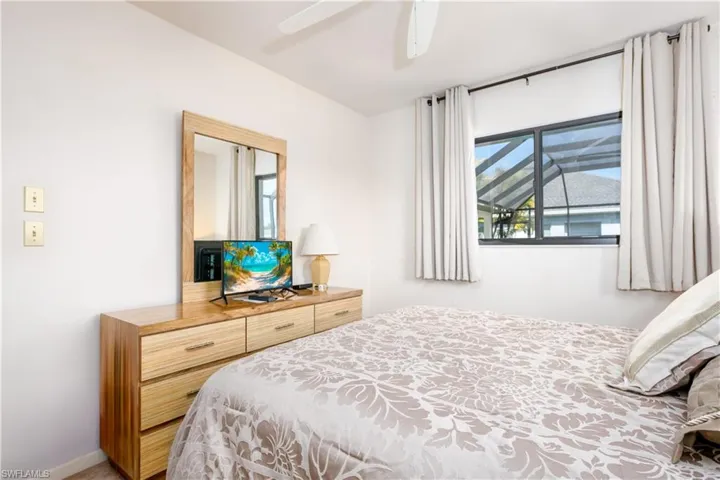 Bedroom featuring a window with exterior screen enclosure views, a ceiling fan, and light-toned walls