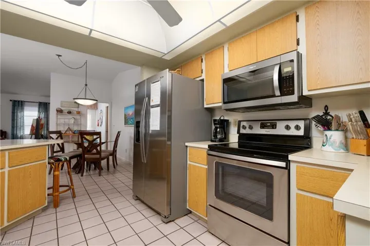 Kitchen featuring stainless steel appliances, light wood-finish cabinetry, and neutral tile flooring