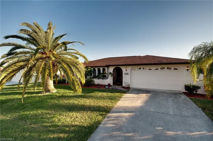 Exterior featuring a two-car garage, concrete driveway, and mature palm trees