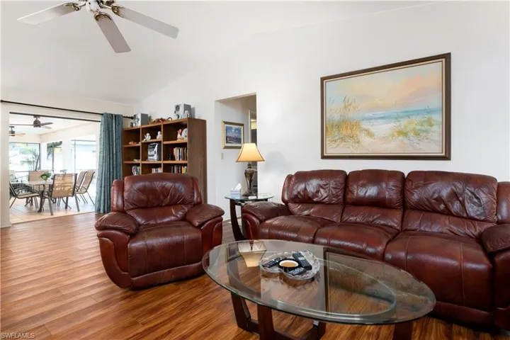 Spacious living area featuring wood-finish flooring, a ceiling fan, and white walls