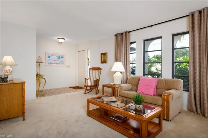 Carpeted living area featuring multiple windows, recessed ceiling light, and a tiled entry