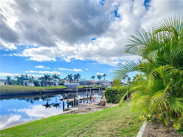 Canal-front property featuring a private dock with boat lift and concrete seawall