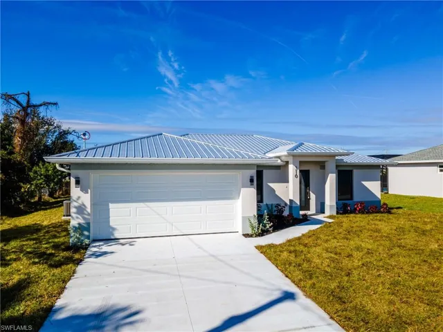 View of front of house with a front yard, stucco siding, and a metal roof
