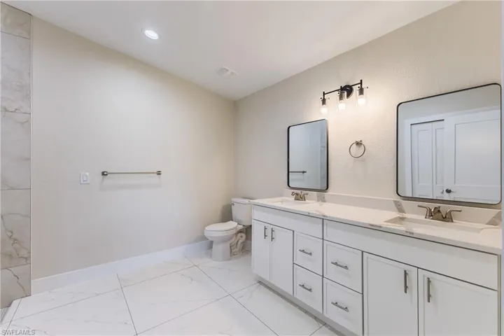 Full bath with light marble finish flooring and double vanity