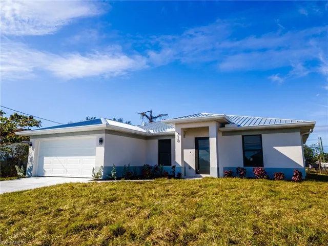 View of front of house with a garage, a standing seam roof, and a front yard