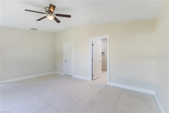 Unfurnished room with light marble finish floors and ceiling fan