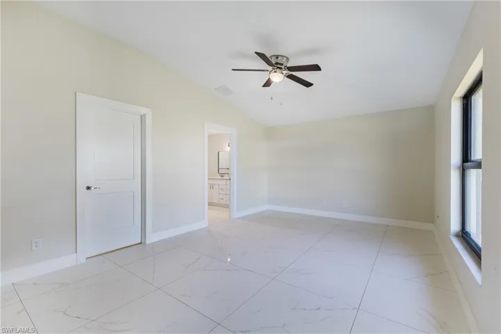 Spare room with light marble finish flooring, vaulted ceiling, and ceiling fan