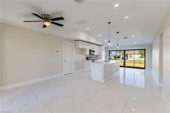 Kitchen with white cabinets, open floor plan, recessed lighting, pendant lighting, and lofted ceiling