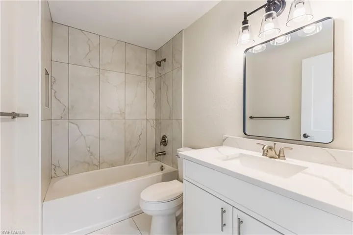 Full bath with shower / bathtub combination, vanity, and a textured wall