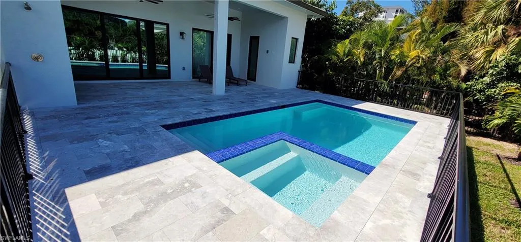 View of swimming pool with a patio area, outdoor shower, a pool with connected hot tub, and ceiling fan
