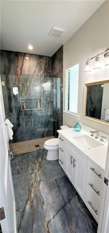 Bathroom with vanity and a marble finish shower