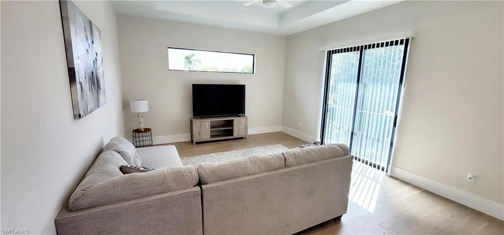 Upstairs Living area with light wood finished floors, ceiling fan, and a tray ceiling