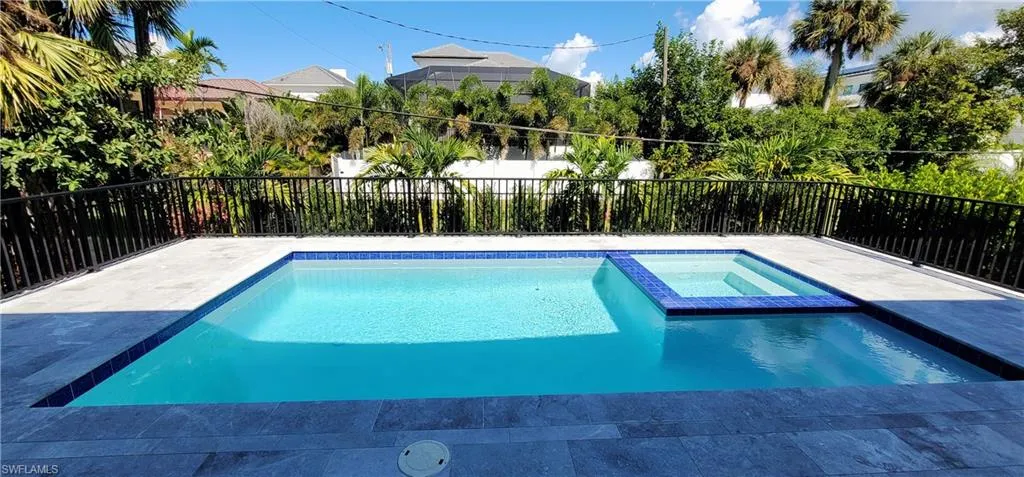 View of pool with a fenced backyard and a pool with connected hot tub