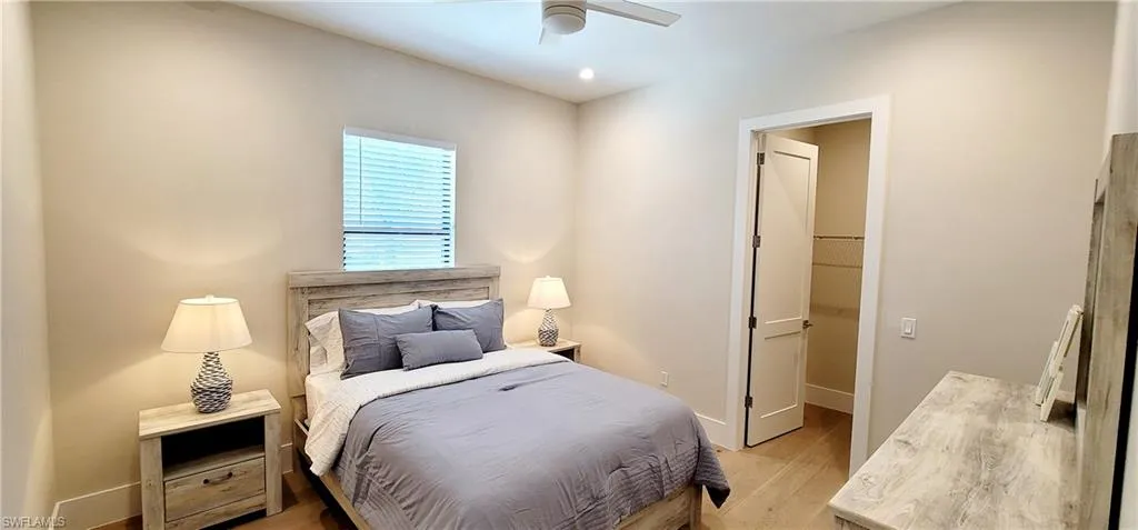 Bedroom with light wood-type flooring, a ceiling fan, and a walk in closet
