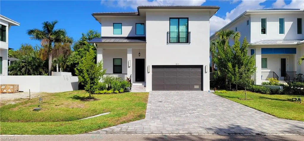 View of front of home with a standing seam roof, a metal roof, stucco siding, an attached garage, and decorative driveway