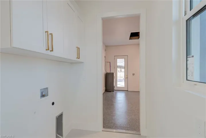 Laundry area featuring hookup for a washing machine, electric dryer hookup, electric water heater, and cabinet space