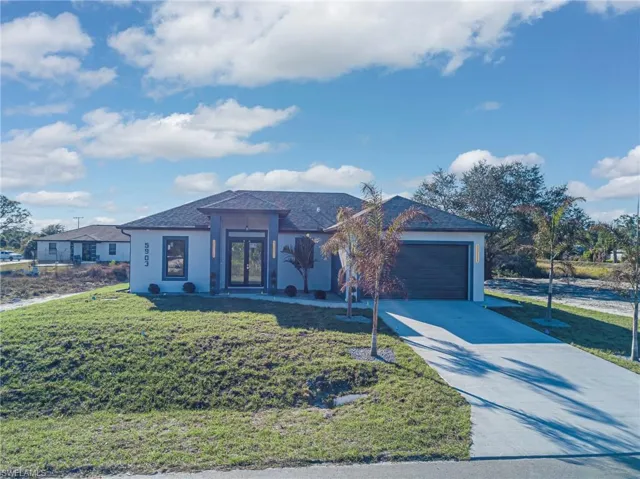 Single story home featuring a front yard, a garage, concrete driveway, and stucco siding
