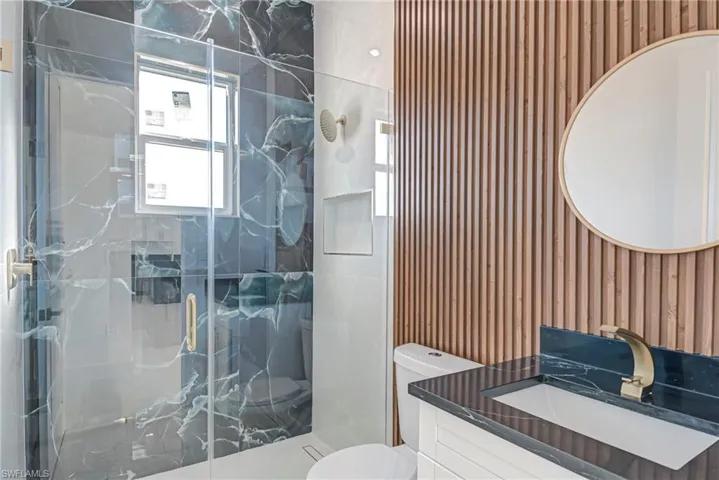 Full bathroom featuring vanity, wallpapered walls, and a marble finish shower