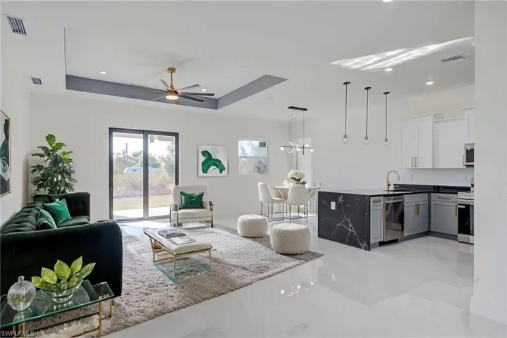 Living room with a tray ceiling, ceiling fan, and recessed lighting