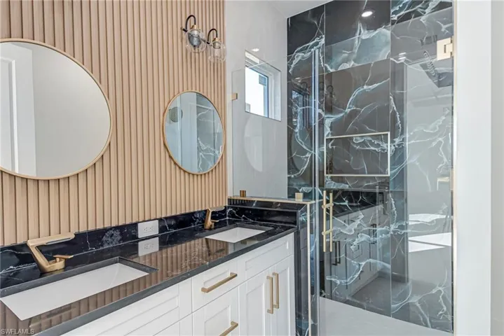 Bathroom with a marble finish shower and double vanity