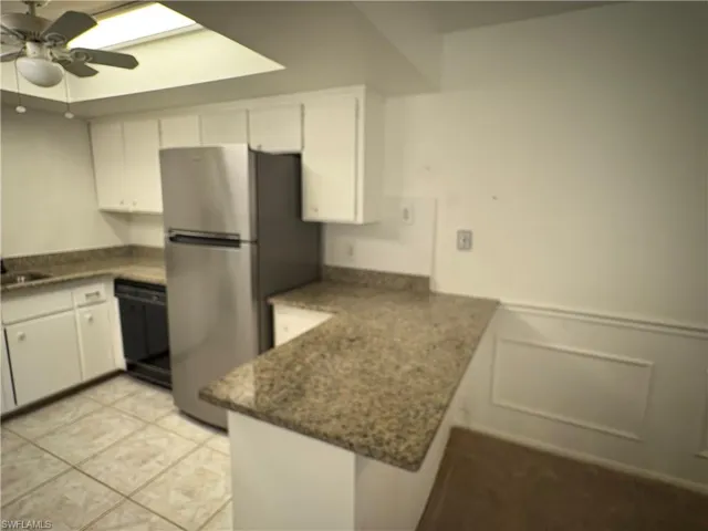 Kitchen with white cabinets, a peninsula, dishwasher, a ceiling fan, and light tile patterned floors