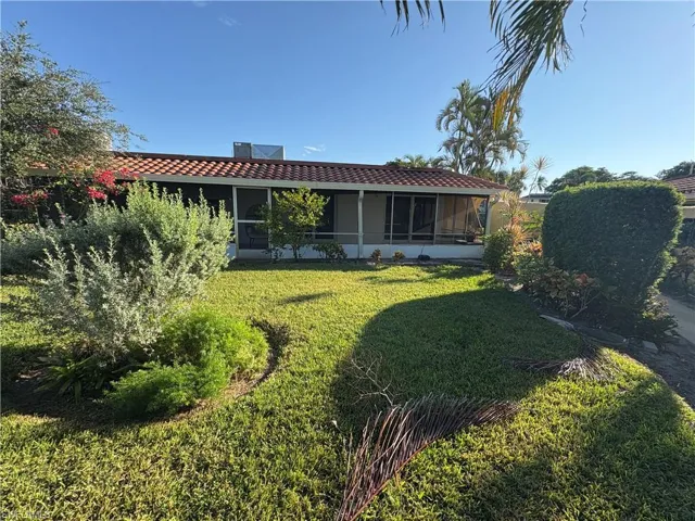Rear view of house with a tile roof, a sunroom, and a yard