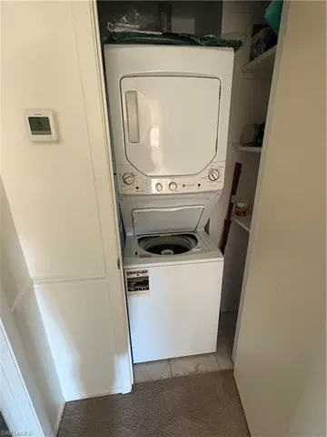 Washroom featuring stacked washer / dryer and light tile patterned floors