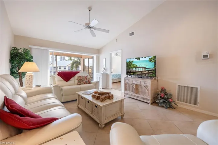 Living room with light tile patterned floors, high vaulted ceiling, and ceiling fan