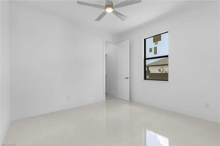 Tiled empty room featuring ceiling fan and plenty of natural light