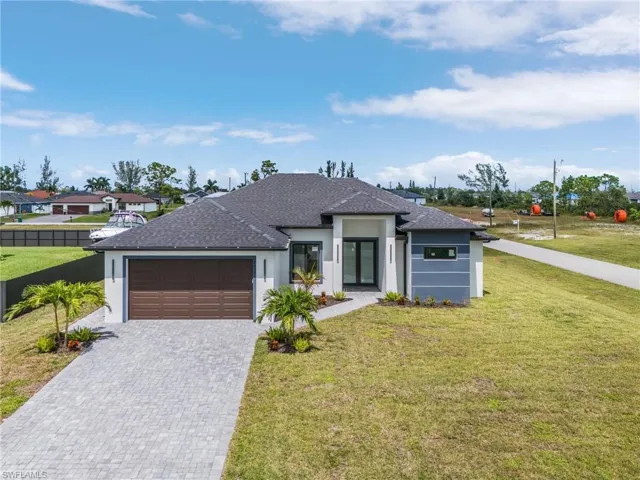 View of front of property featuring a garage and a front lawn