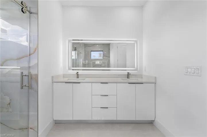 Bathroom featuring tile patterned flooring, vanity, and a shower with door