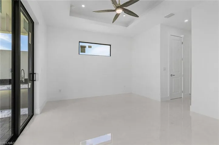 Tiled empty room with ceiling fan and a raised ceiling