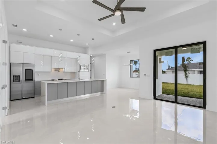 Kitchen with a tray ceiling, a center island, built in appliances, white cabinets, and ceiling fan