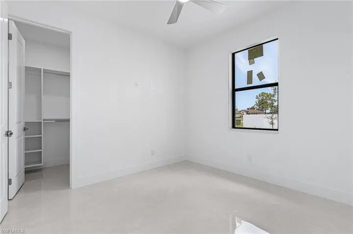 Unfurnished bedroom featuring a spacious closet, a closet, ceiling fan, and light tile patterned flooring