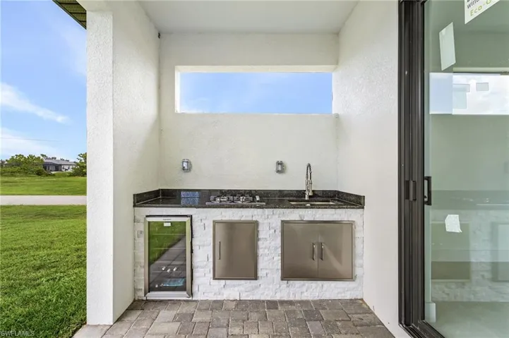 View of patio with wine cooler, an outdoor kitchen, and sink