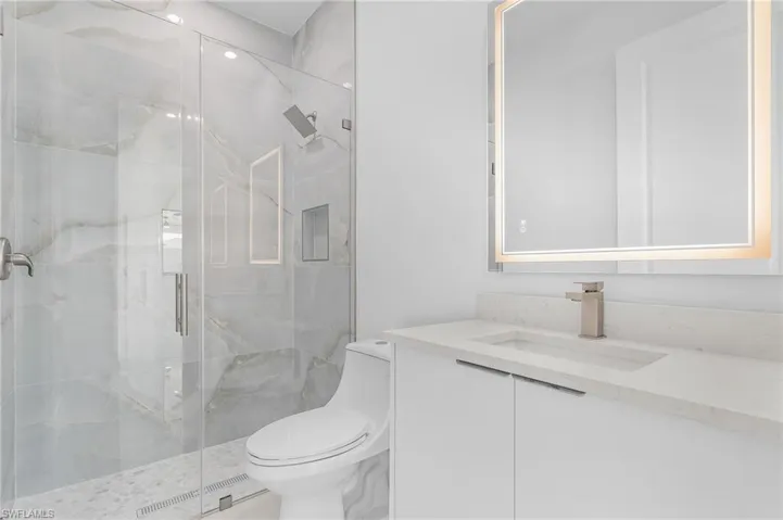 Bathroom featuring walk in shower, vanity, and toilet