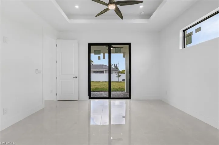 Empty room with a healthy amount of sunlight, ceiling fan, and a raised ceiling